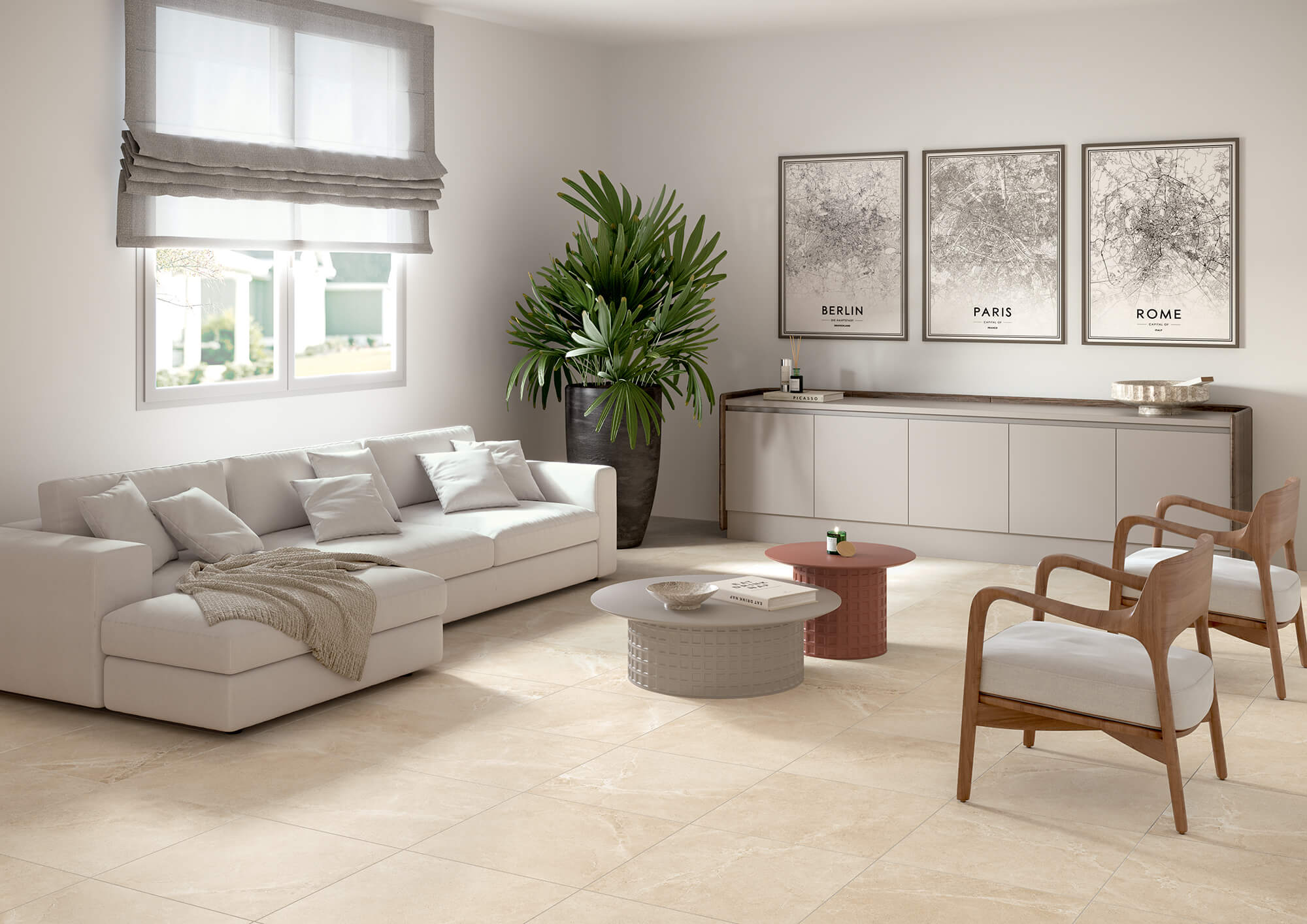 Soggiorno moderno luminoso con pavimento in gres effetto pietra beige, divano chiaro, tavolini rotondi, madia minimal e decorazioni con piante e stampe a parete.